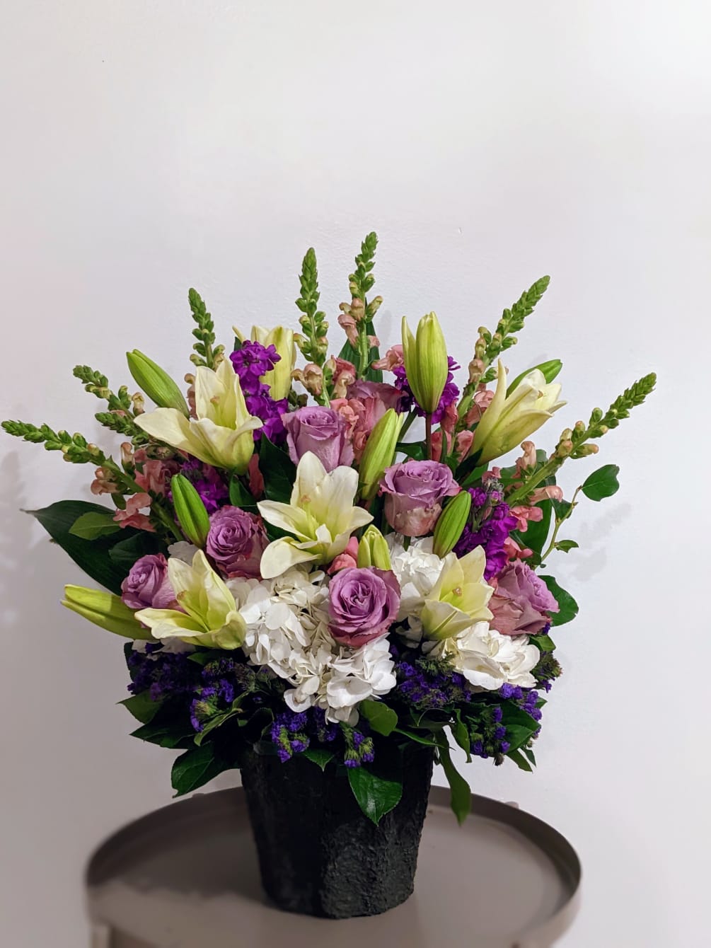 A white and lavender melody of mixed flowers in a paper mache