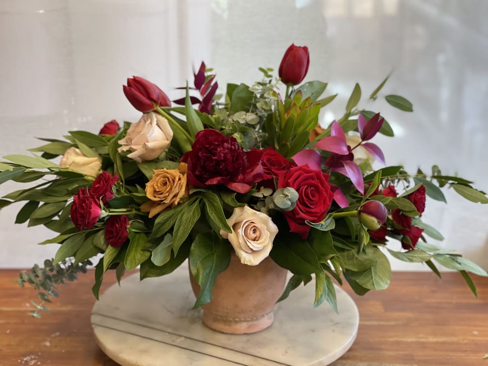 Beautiful wide arrangement, filled with seasonal flowers, burgundy roses and Australian peonies