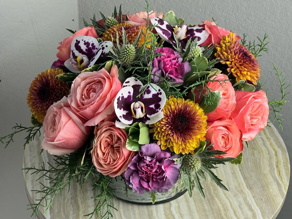 A low and lush mixed floral arrangement with seasonal colors and tons