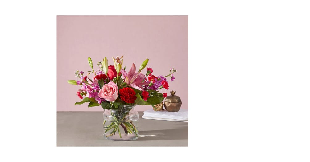 Clear low vase with pink and red flowers.