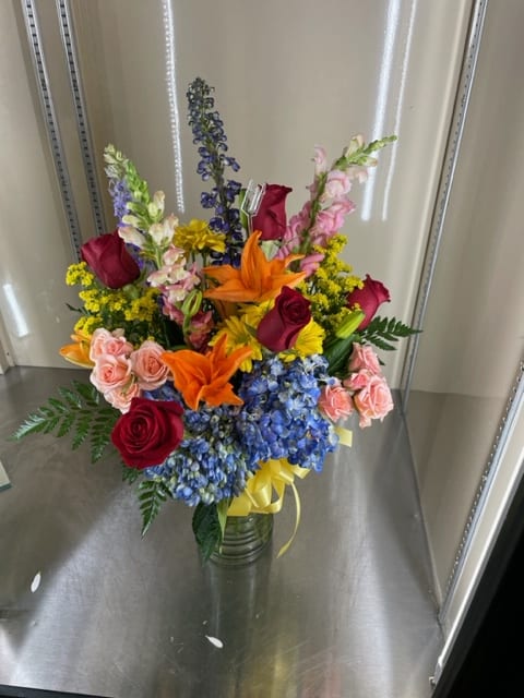 Mixed cut arrangement with red roses, peach/pink spray roses, pink snapdragon, blue