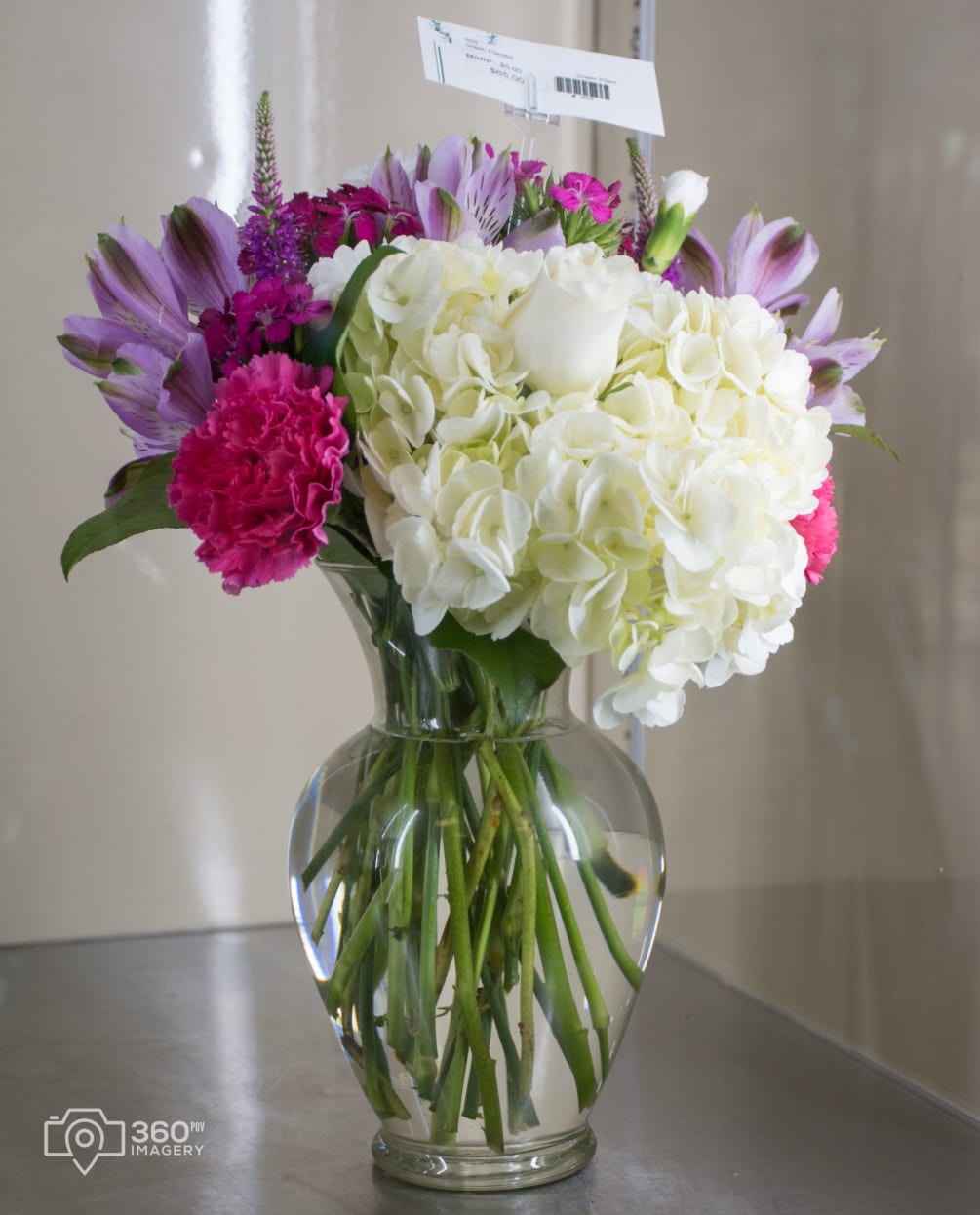 White hydrangea, white rose, hot pink carnations, lavender alstroemeria, accented with pinks
