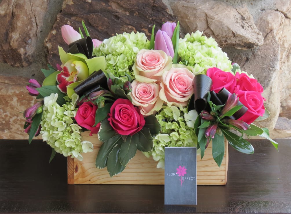 Roses, hydrangeas, and seasonal flowers arranged on a wood box. More colors