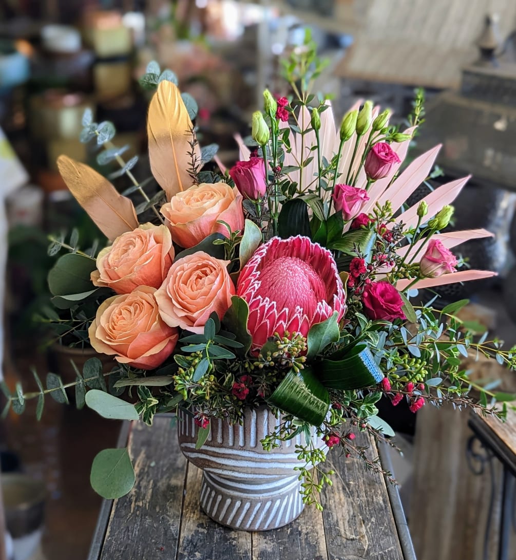 Roses, protea, tulips, veronica and mixed greens in a footed compote, accented