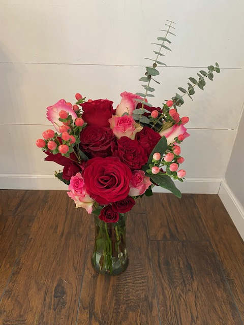 Red and pink roses with pink hypericum and eucalyptus in a clear