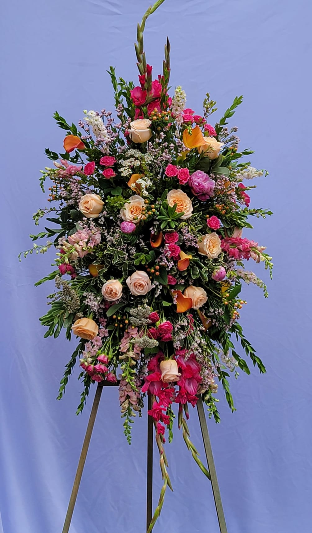 This bright and elegant sympathy piece features gladiolas, roses and more in