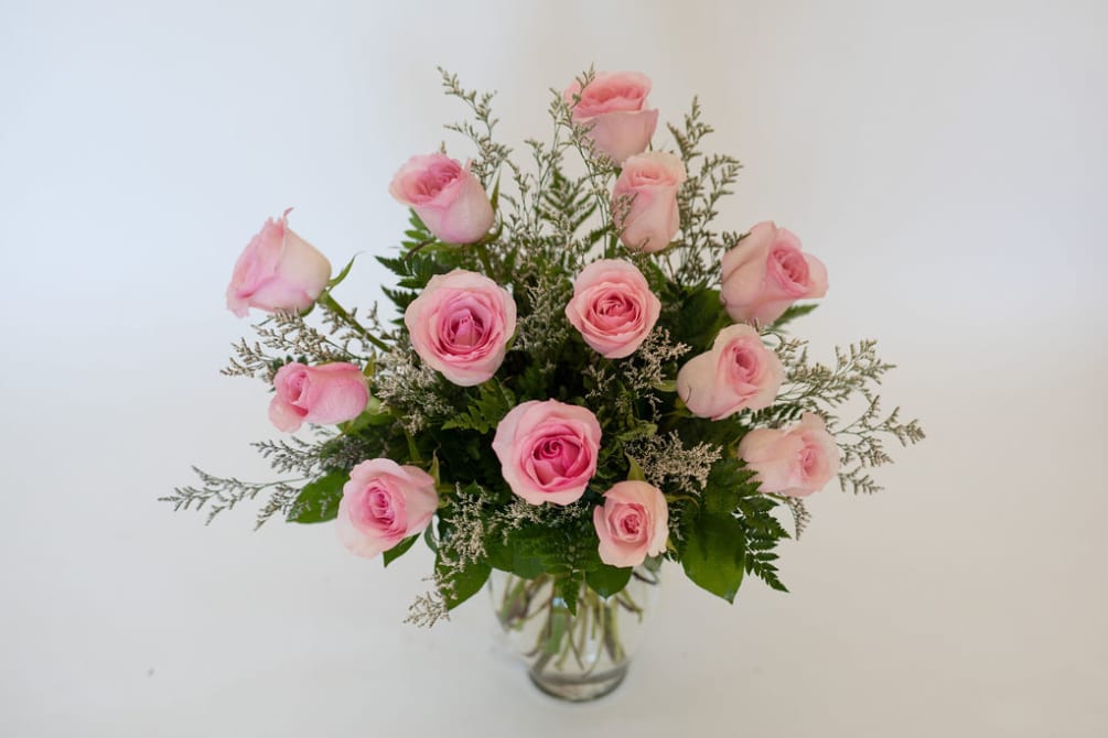 Blush, long-stem roses expertly designed in a vase with beautiful greenery and