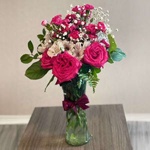 The combination of fuchsia roses, delicate carnations, white alstroemerias, and baby&rsquo;s breath