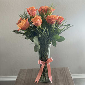 Elegant bouquet of long stem orange roses with assorted greenery all around