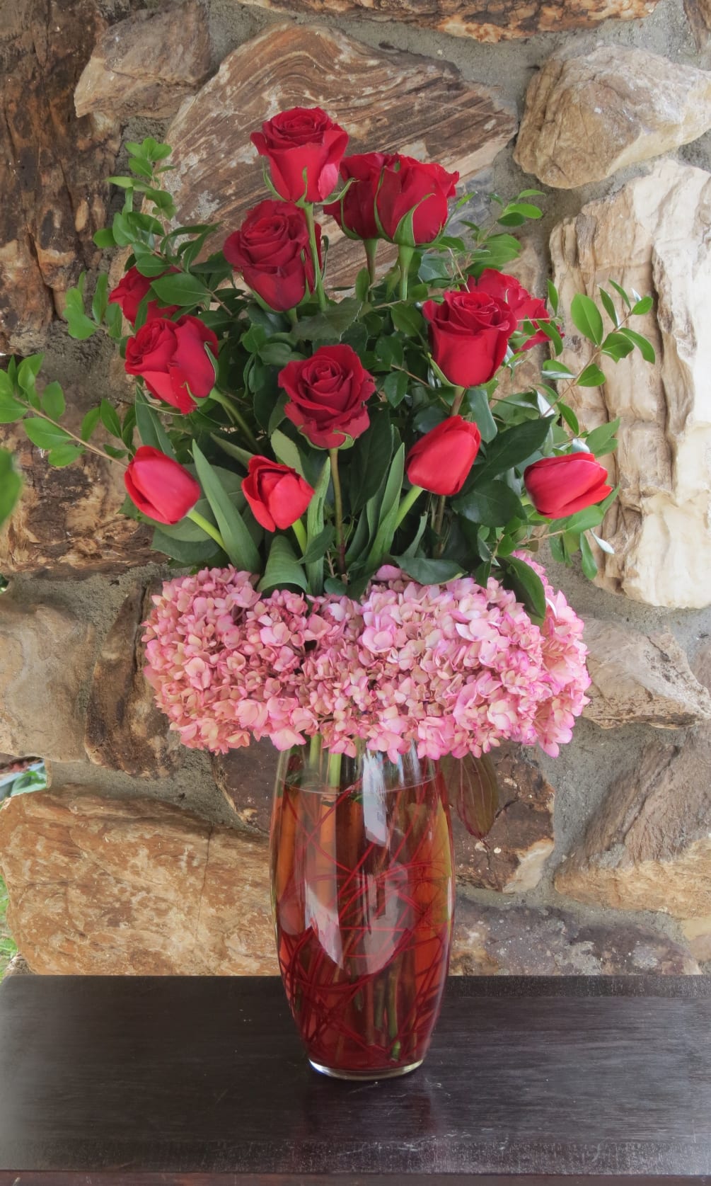 12 Red roses arranged on a glass vase with tulips and Hydrangeas
