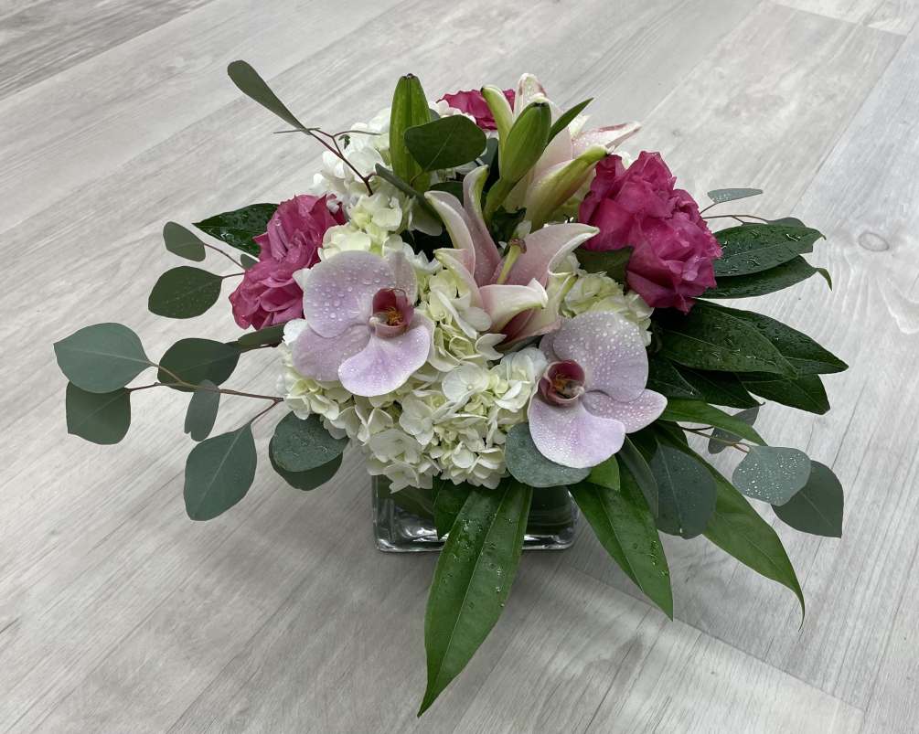 Glass cube, pink roses, pink orchids, white hydrangea, pink lily 