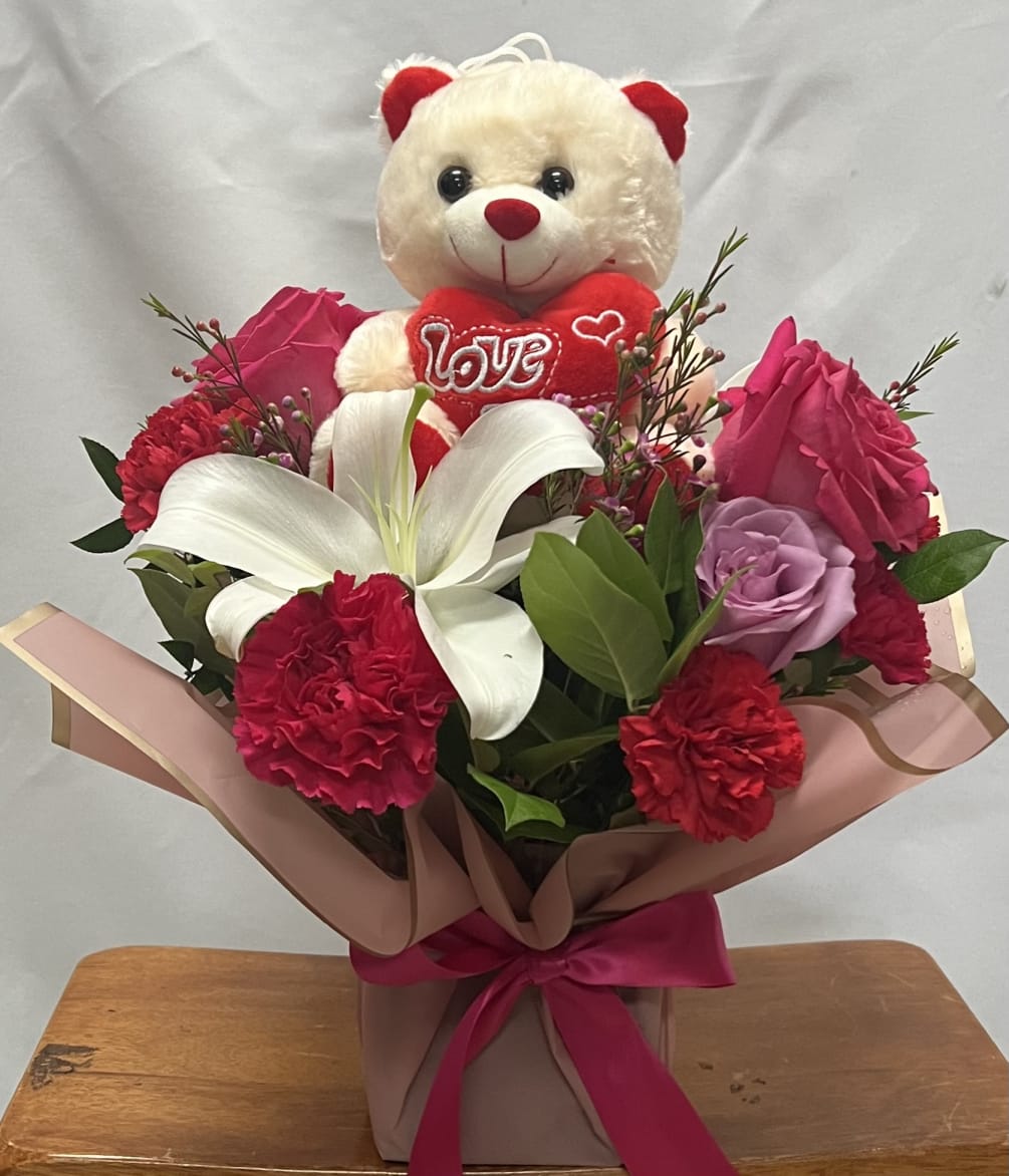 Roses , carnations , wax flowers and a lily with a teddy