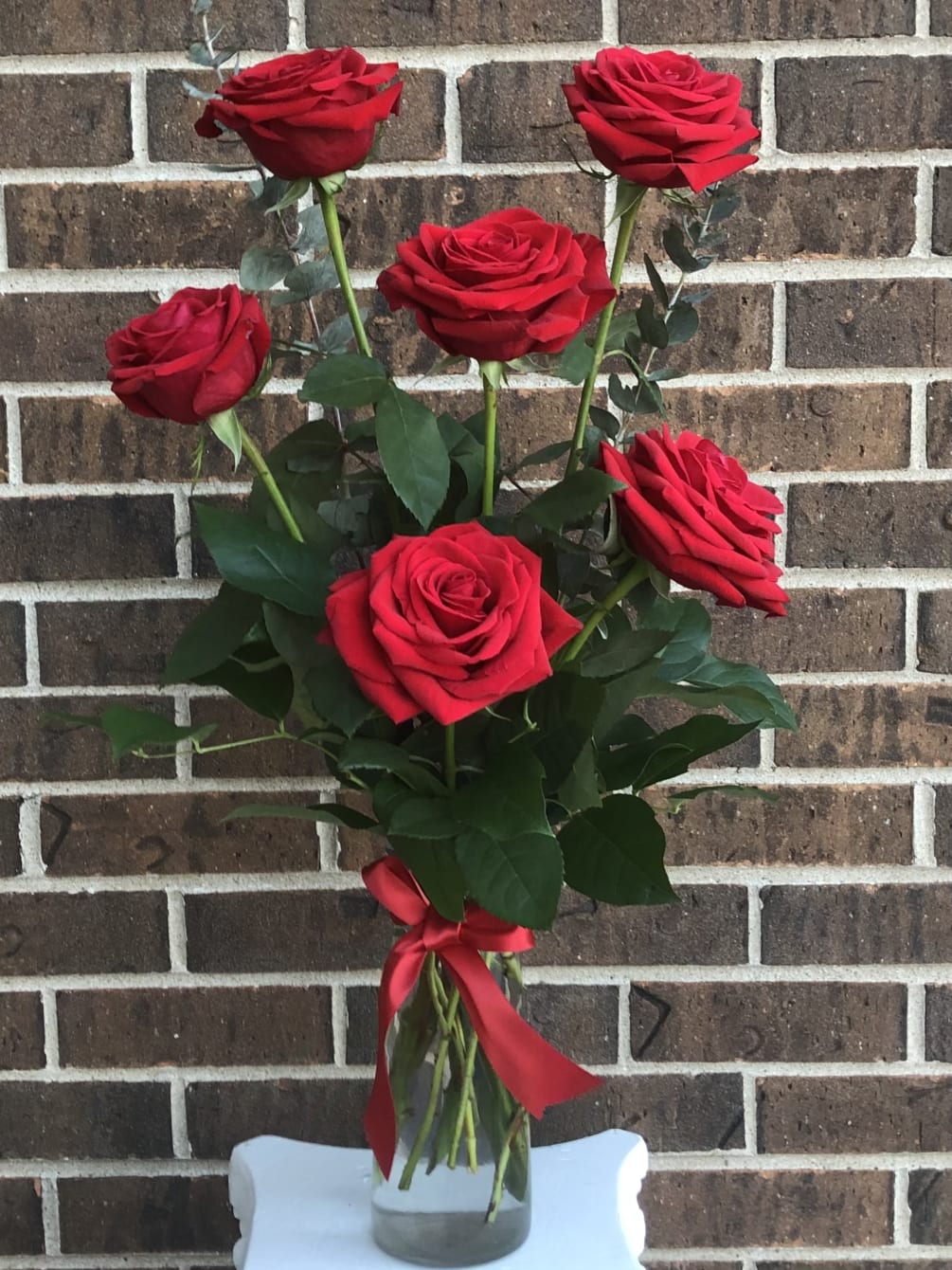 Six beautiful red roses in a vase with red ribbon.