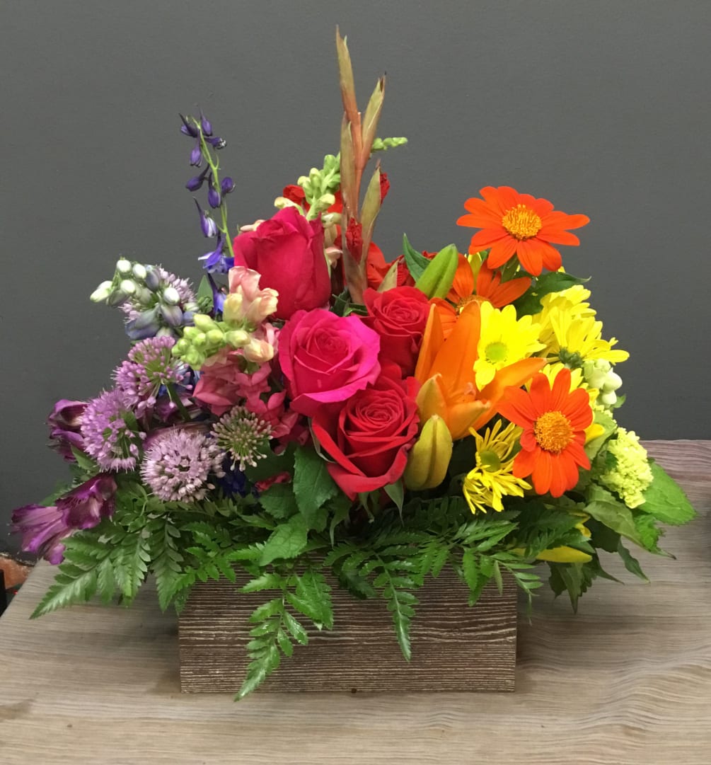 Rainbow design using different varieties and colors of flowers in a wooden