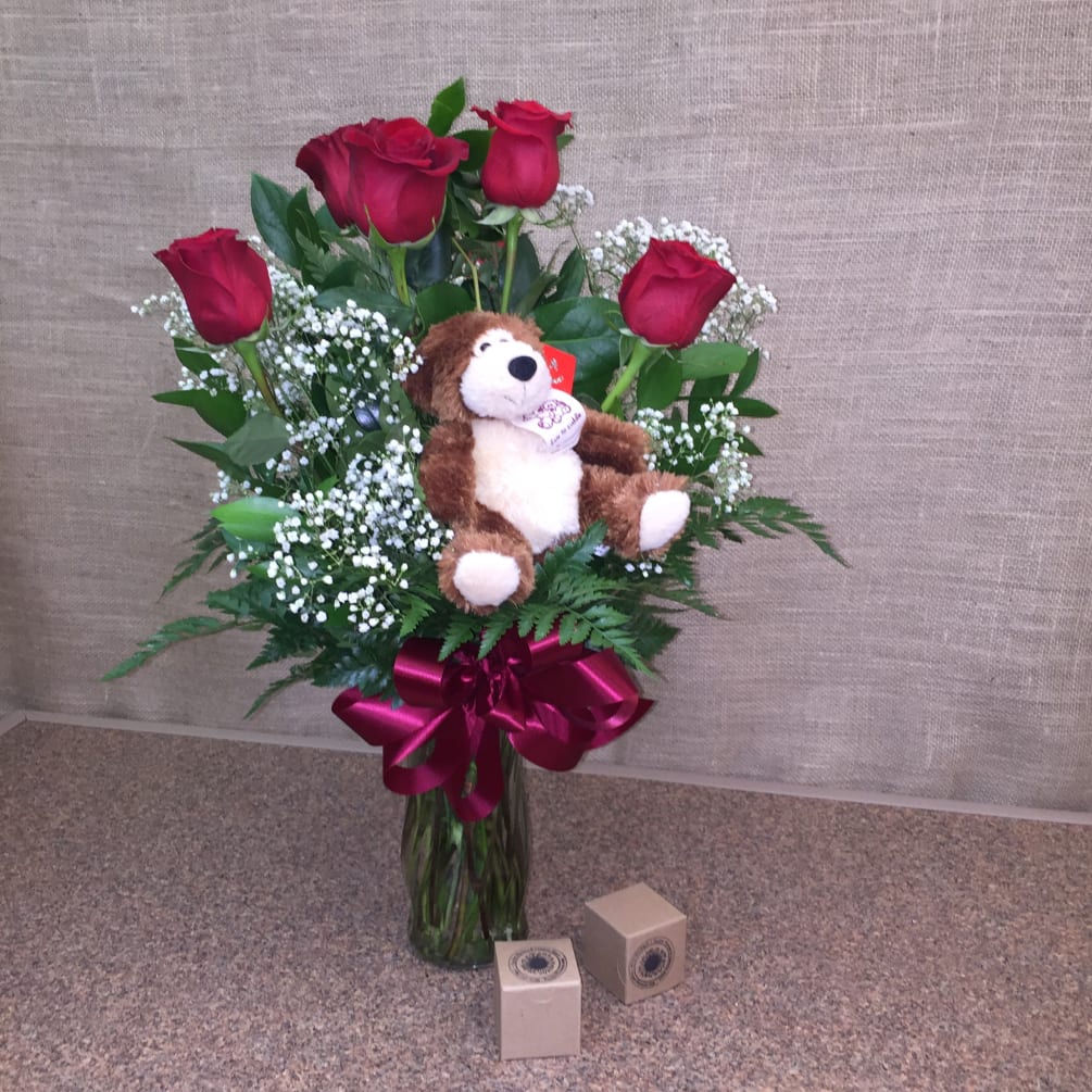 One half dozen long-stemmed red roses arranged in a glass vase with