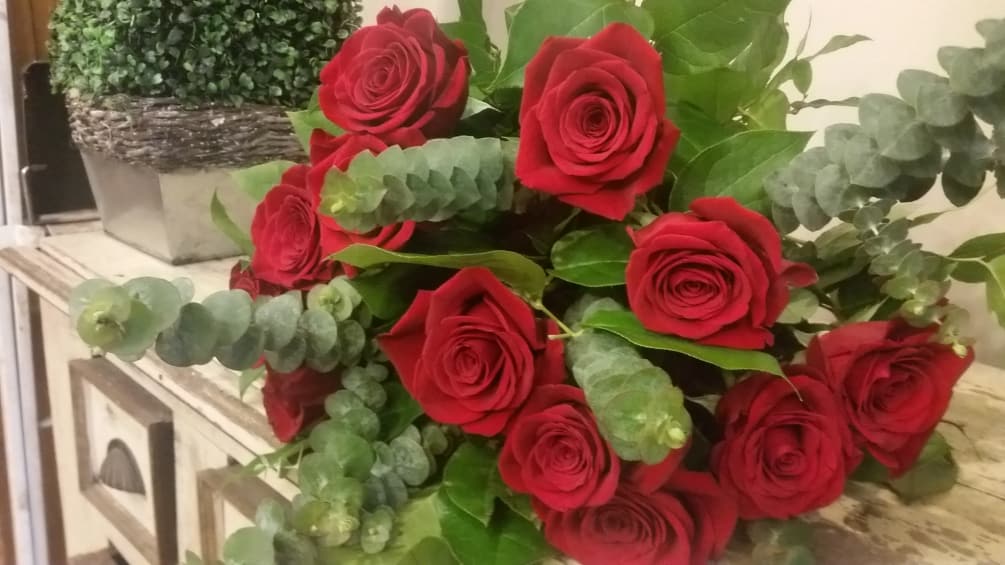 One dozen long stem red roses in a wrapped bouquet. 