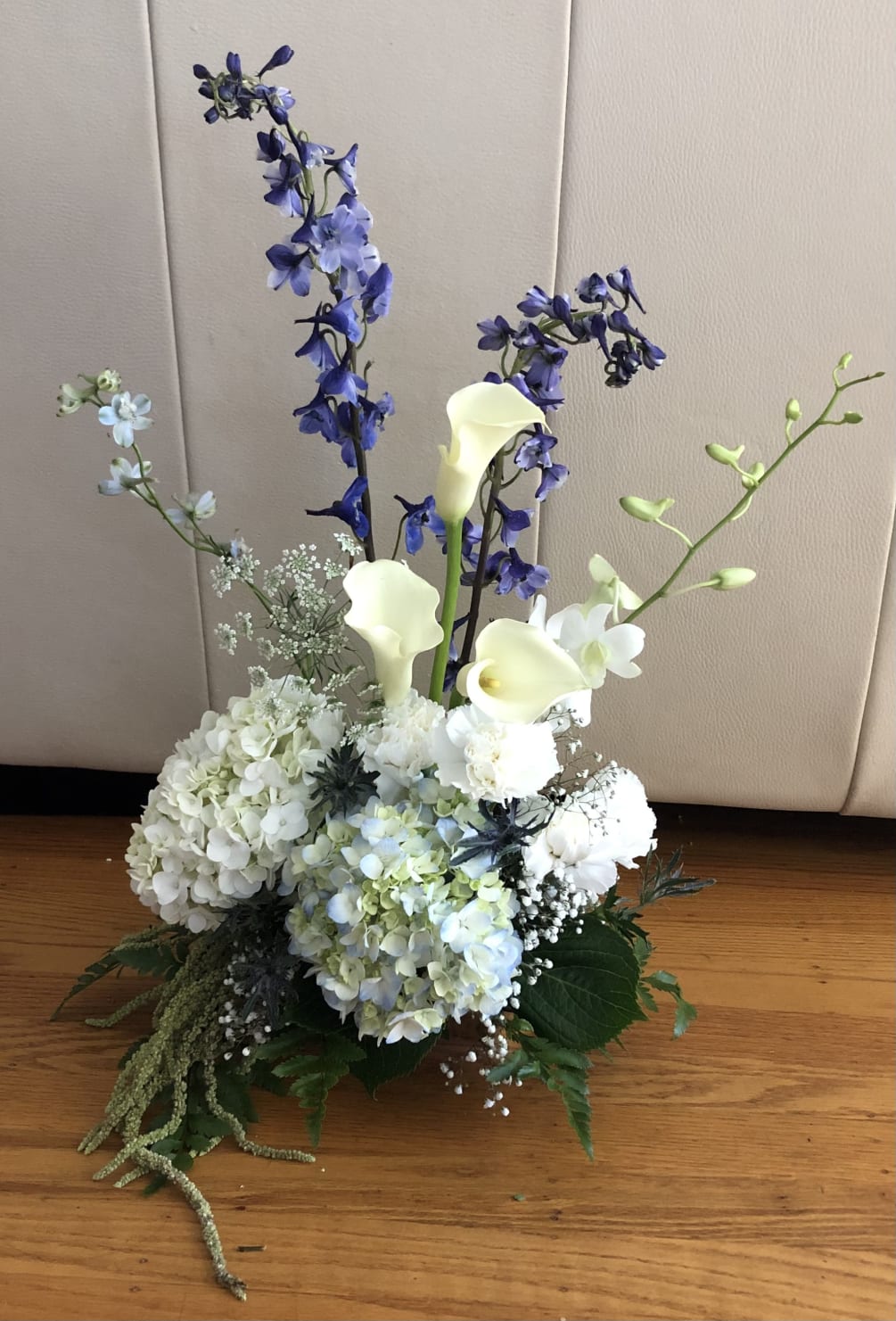 A wintery blue arrangement with calla lillies, carnations, hydrangea, and orchid. 