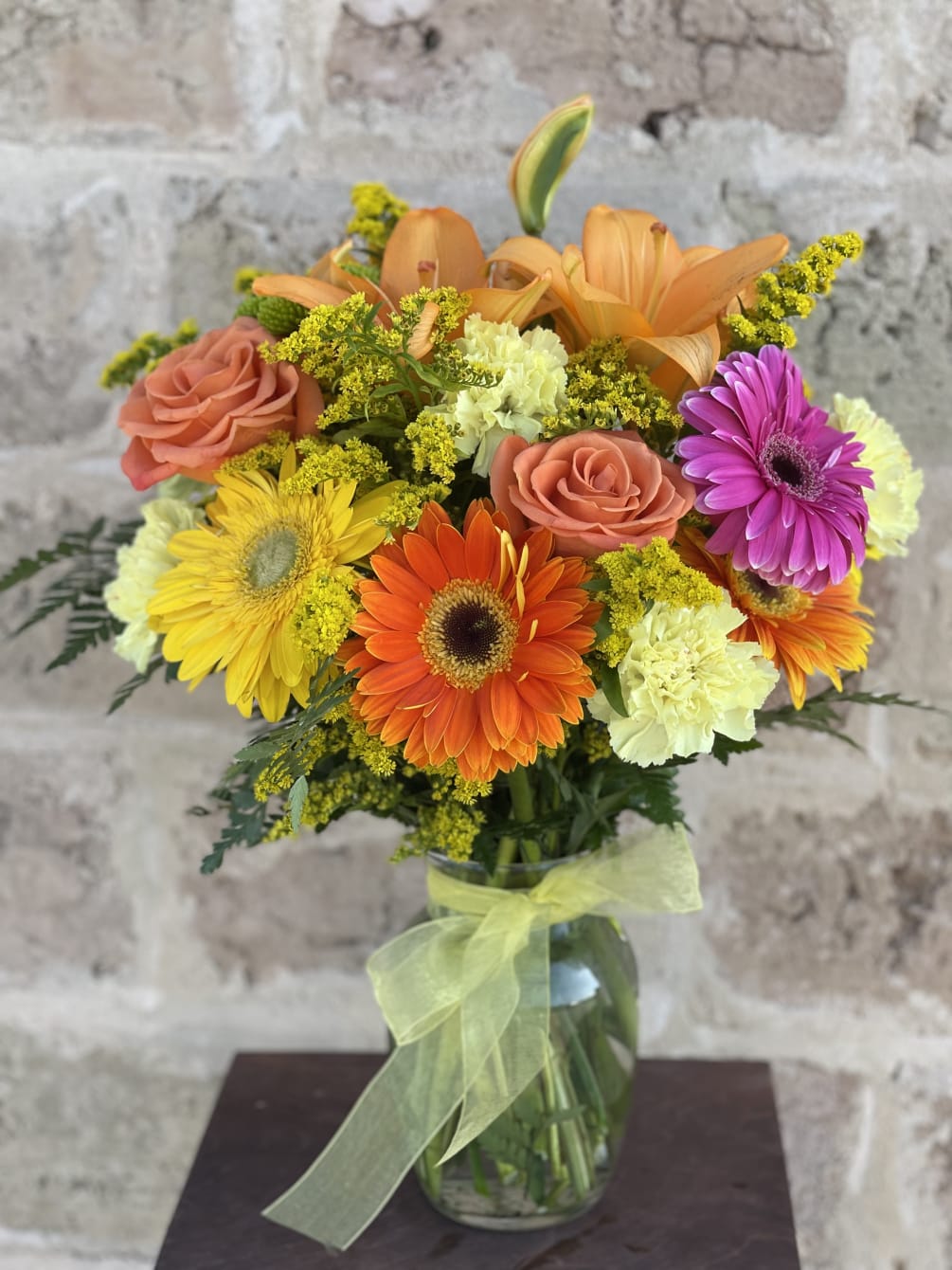 This striking bouquet of yellow and orange assorted flowers in a clear