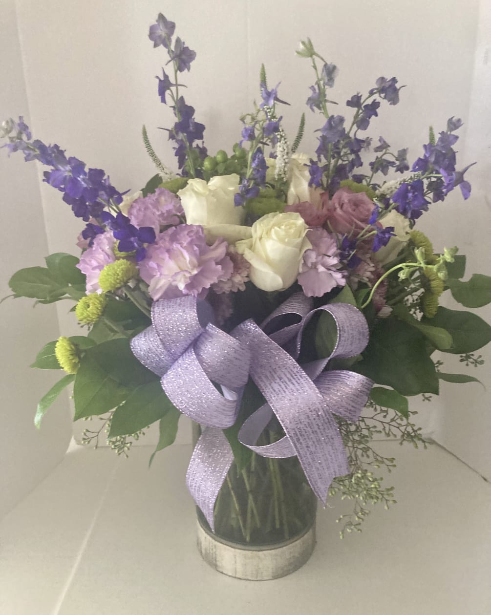 Lavender, white and green season blooms in a custom vase.