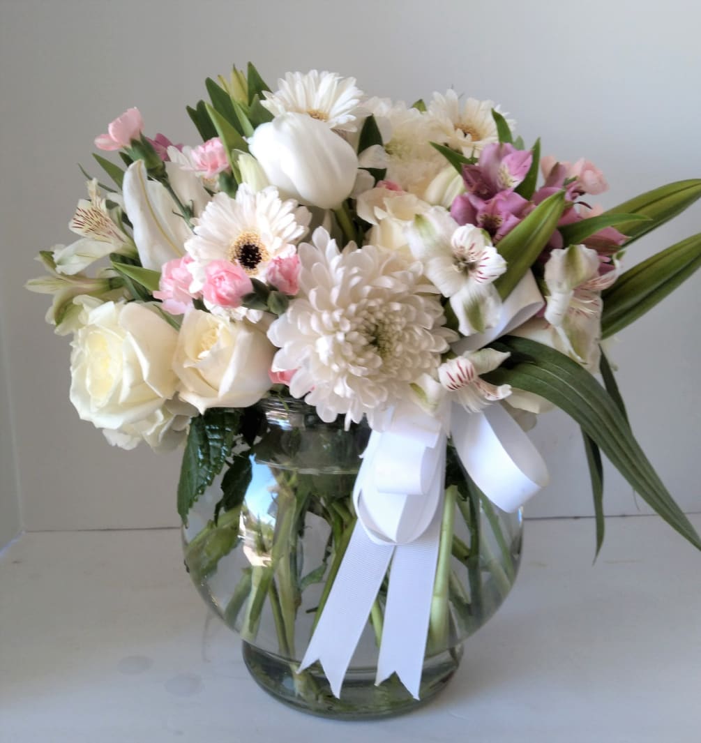 A custom vase filled with white and pink seasonal blooms.