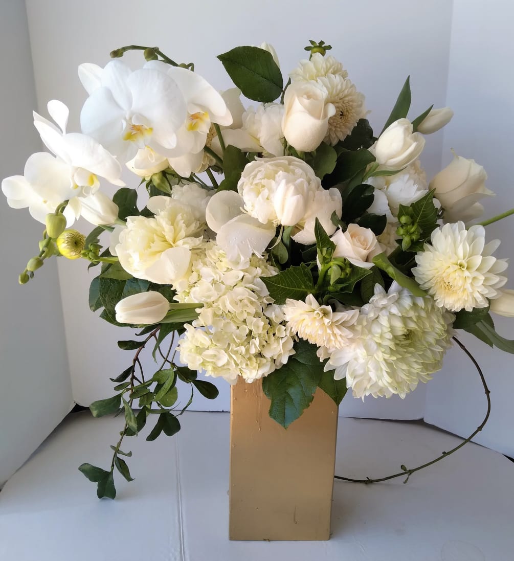 All white seasonal blooms fill a custom container, sure to bring beauty