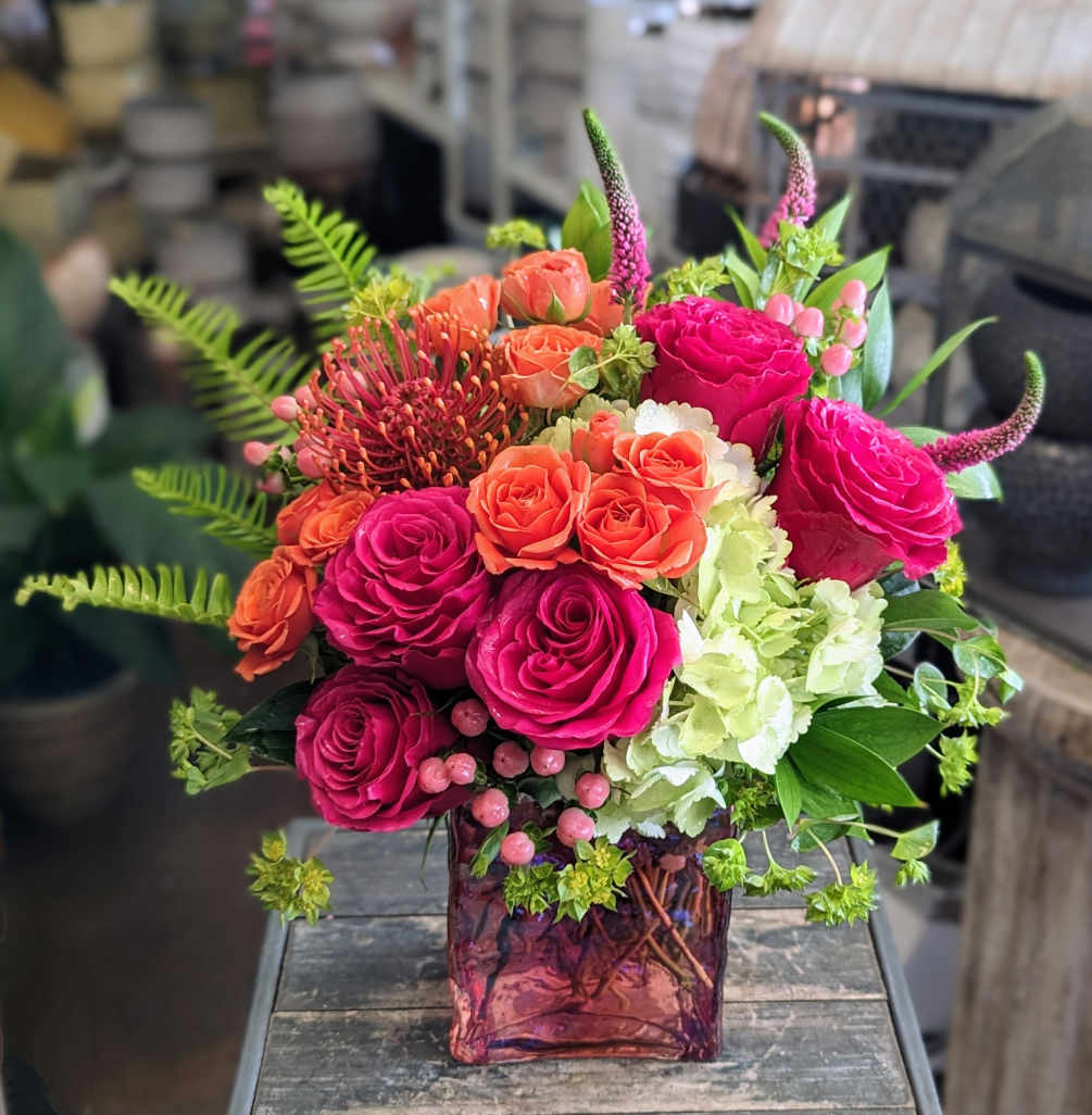 Roses, spray roses, hydrangea, and pincushion protea in a vibrant mix of