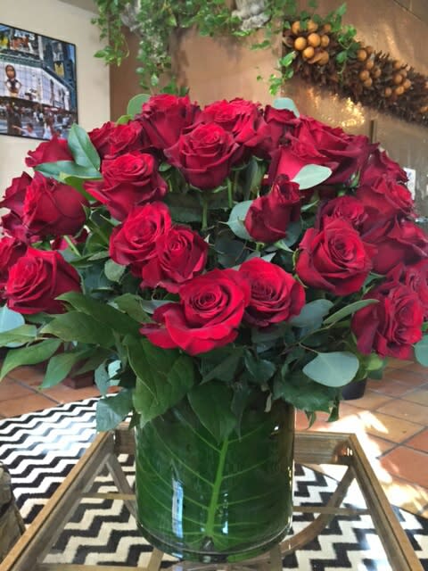 5 dozen beautiful premium red roses surrounded by complementary greenery in a