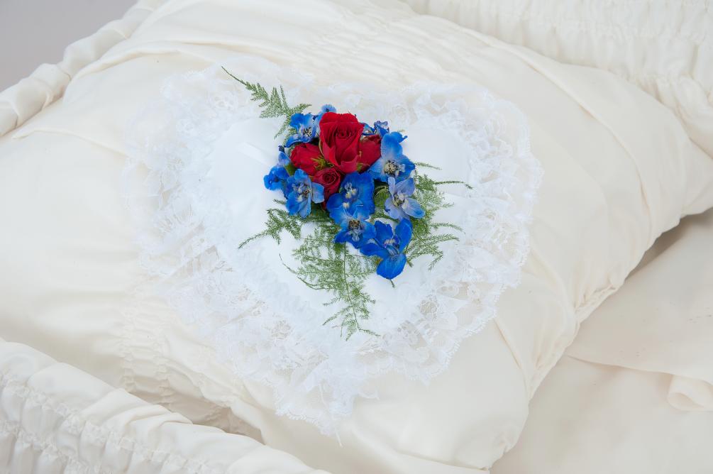 A satin heart pillow enhanced with a touch of flowers.