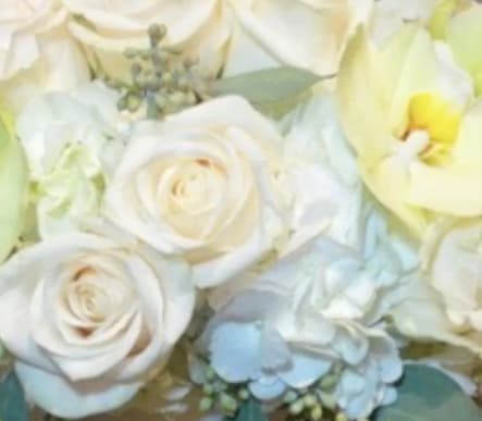 The arrangement includes a lovely mix of white seasonal flowers chosen by