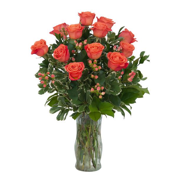 Orange Roses and Berries arranged in a clear glass vase.