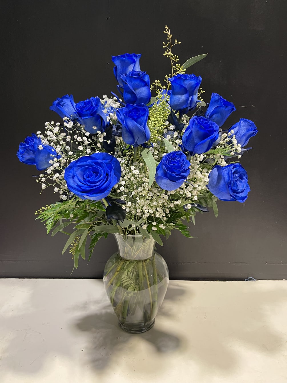 Harmonious dozen blue roses designed with delicacy and detail.