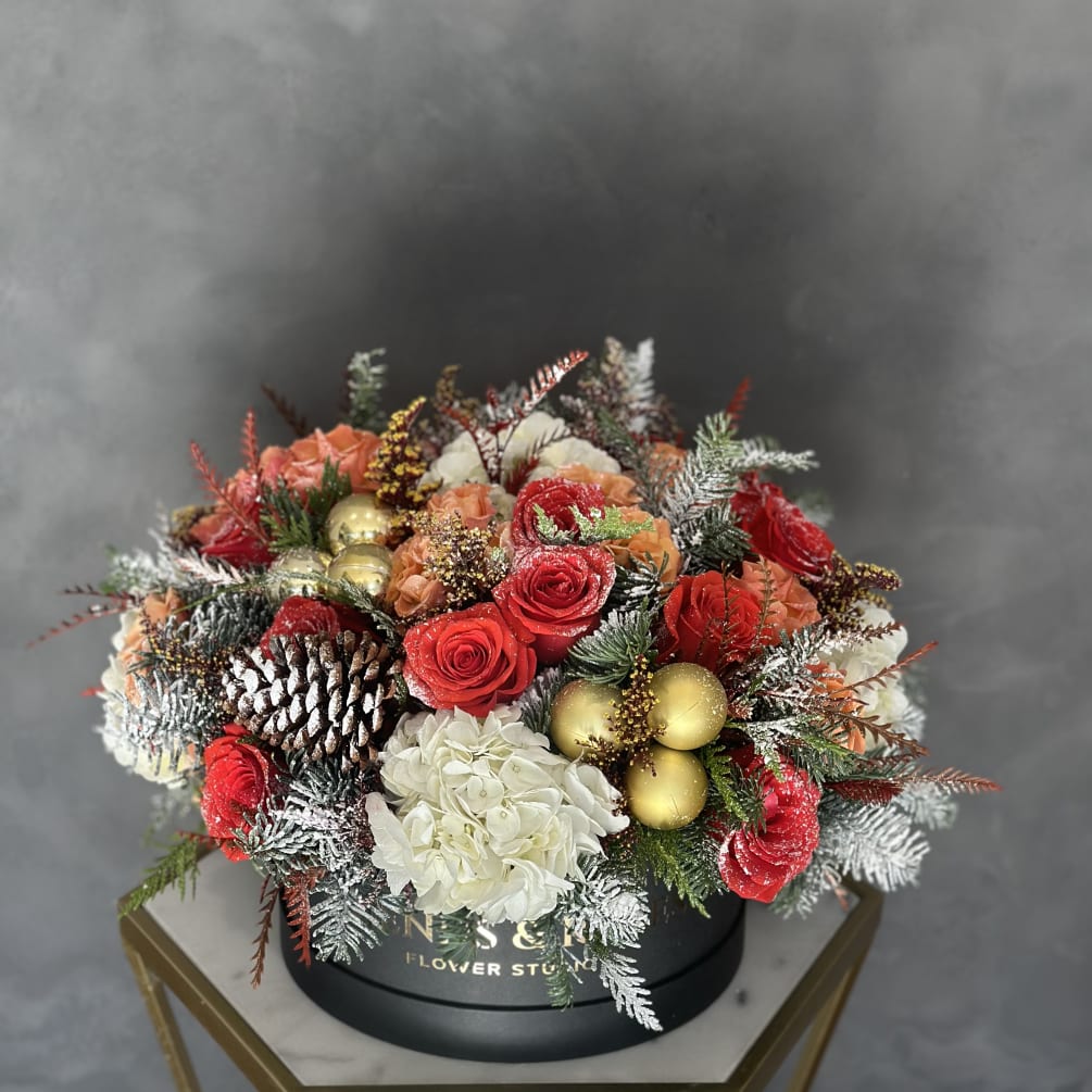 Beautiful Christmas-themed arrangement filled with Christmas branches, fresh flowers, and holiday ornaments.