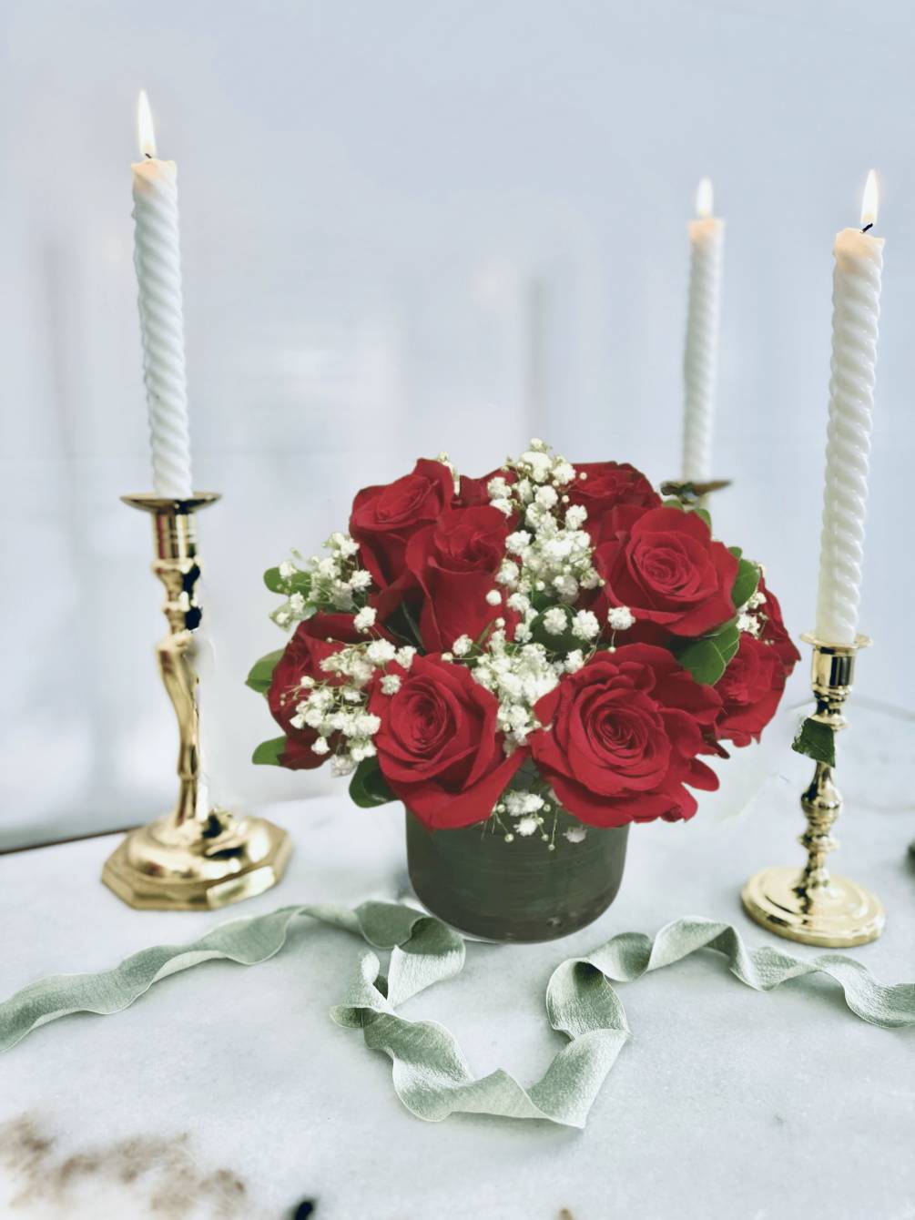 Red roses, pittisporum, and babysbreath arranged in a glass cylinder or cube.

CANDLES