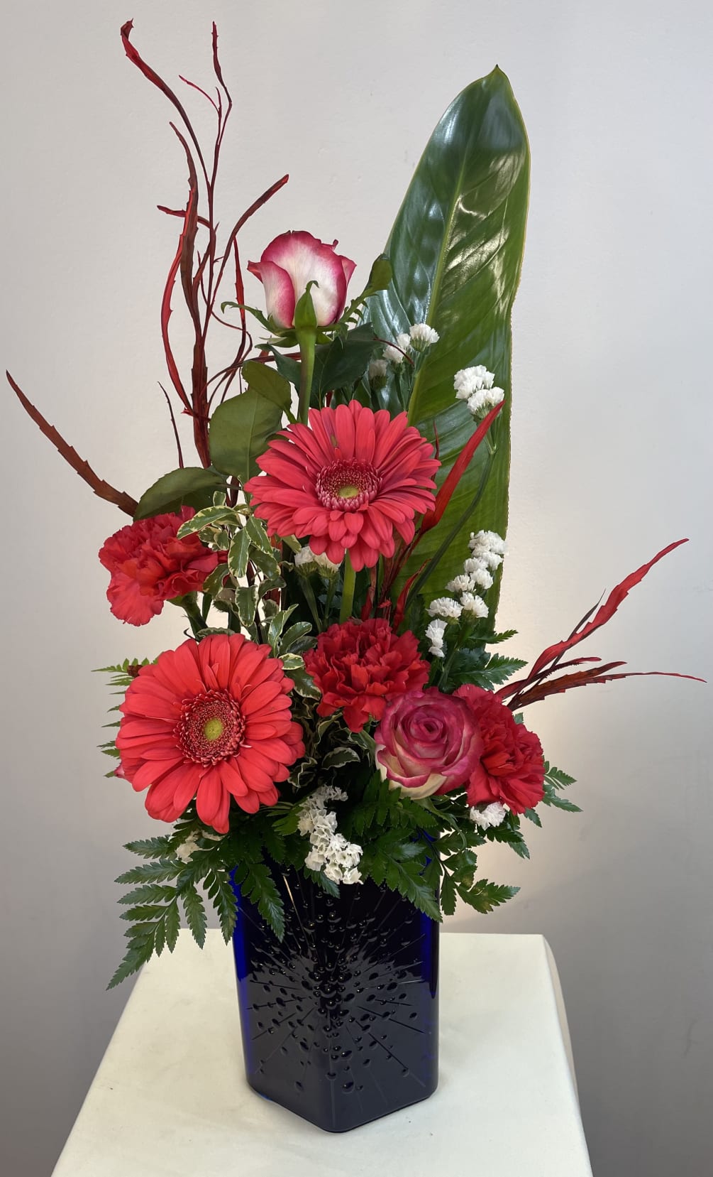 A contemporary des[gn featuring red gerberas in our popular blue starburst vase.