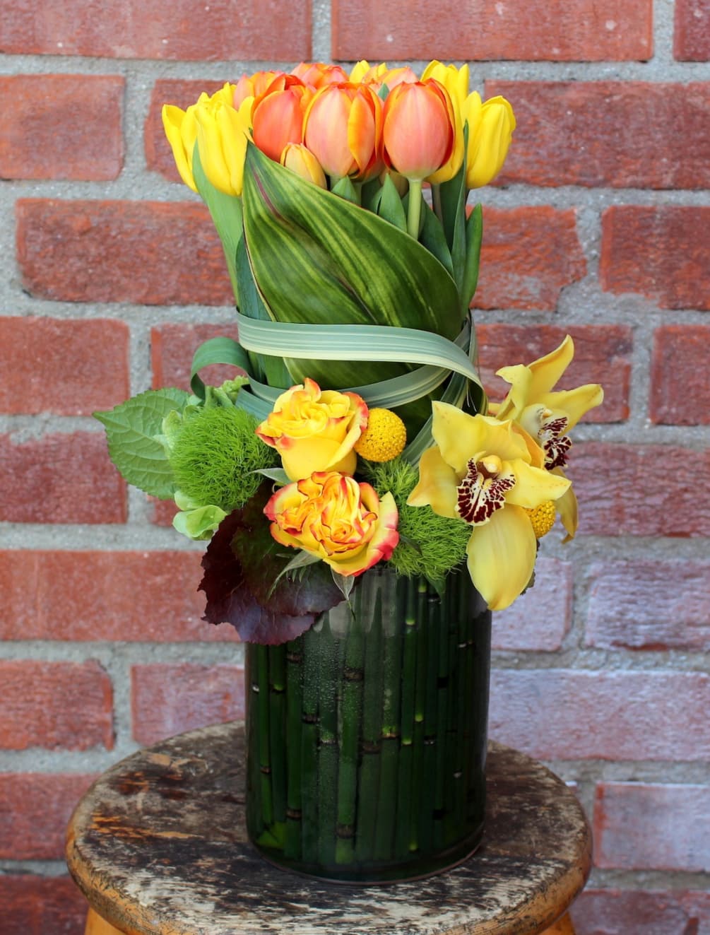 Tulips wrapped with tea leaves and surrounded by roses and orchids. 