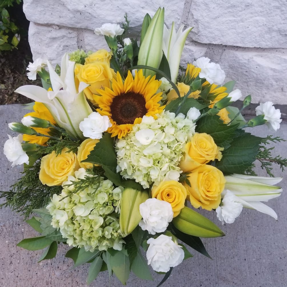 Low and full describes this beautiful combination of lilies, roses, hydrangeas, sunflowers