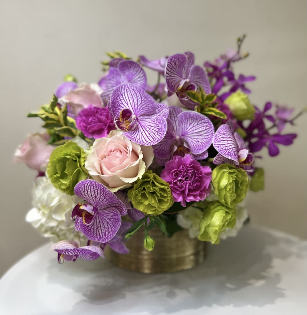 The stunning arrangement features Orchids and other lush blooms in a gorgeous
