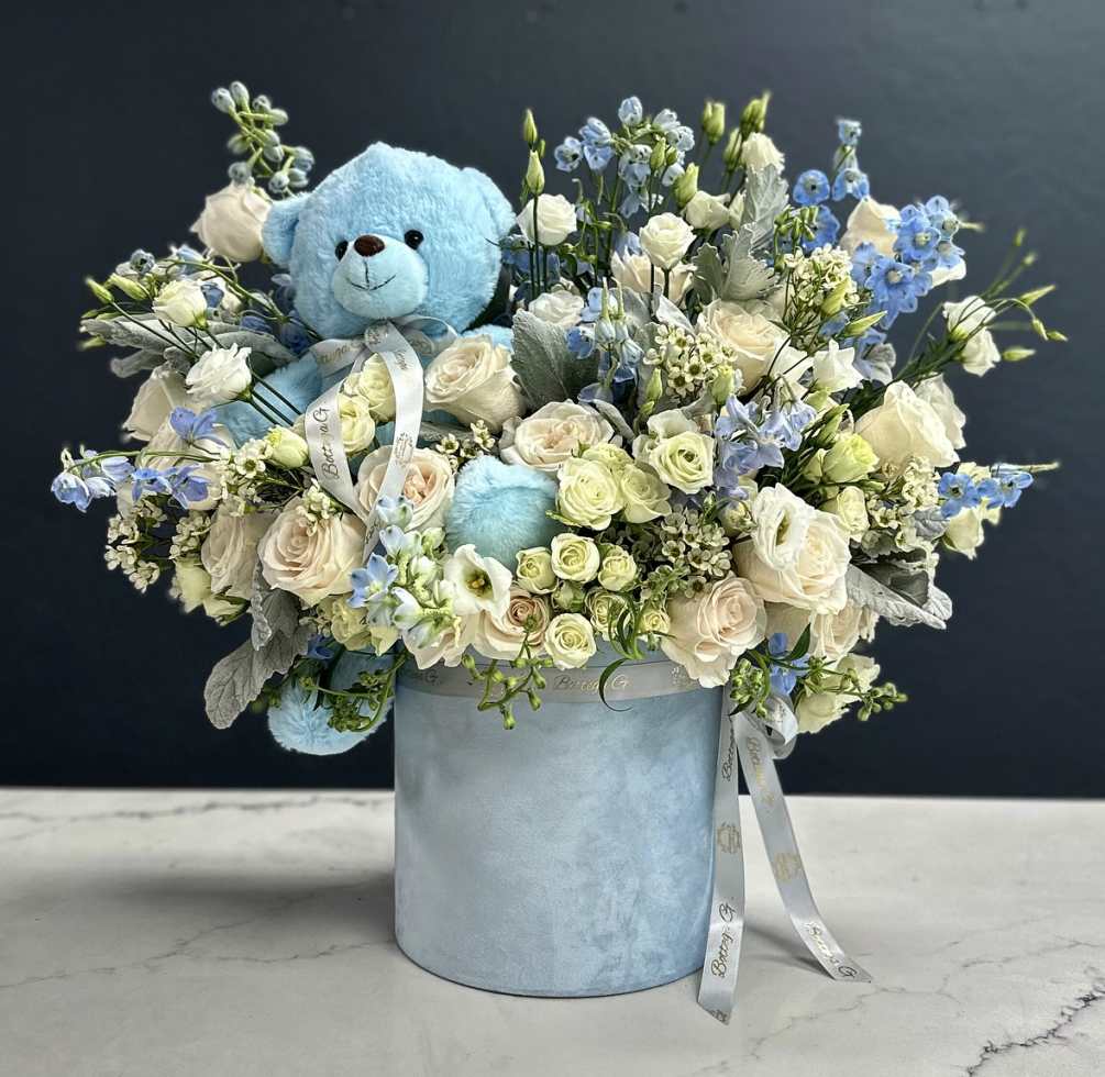 A velvet light blue hat box topped off with specialty roses with