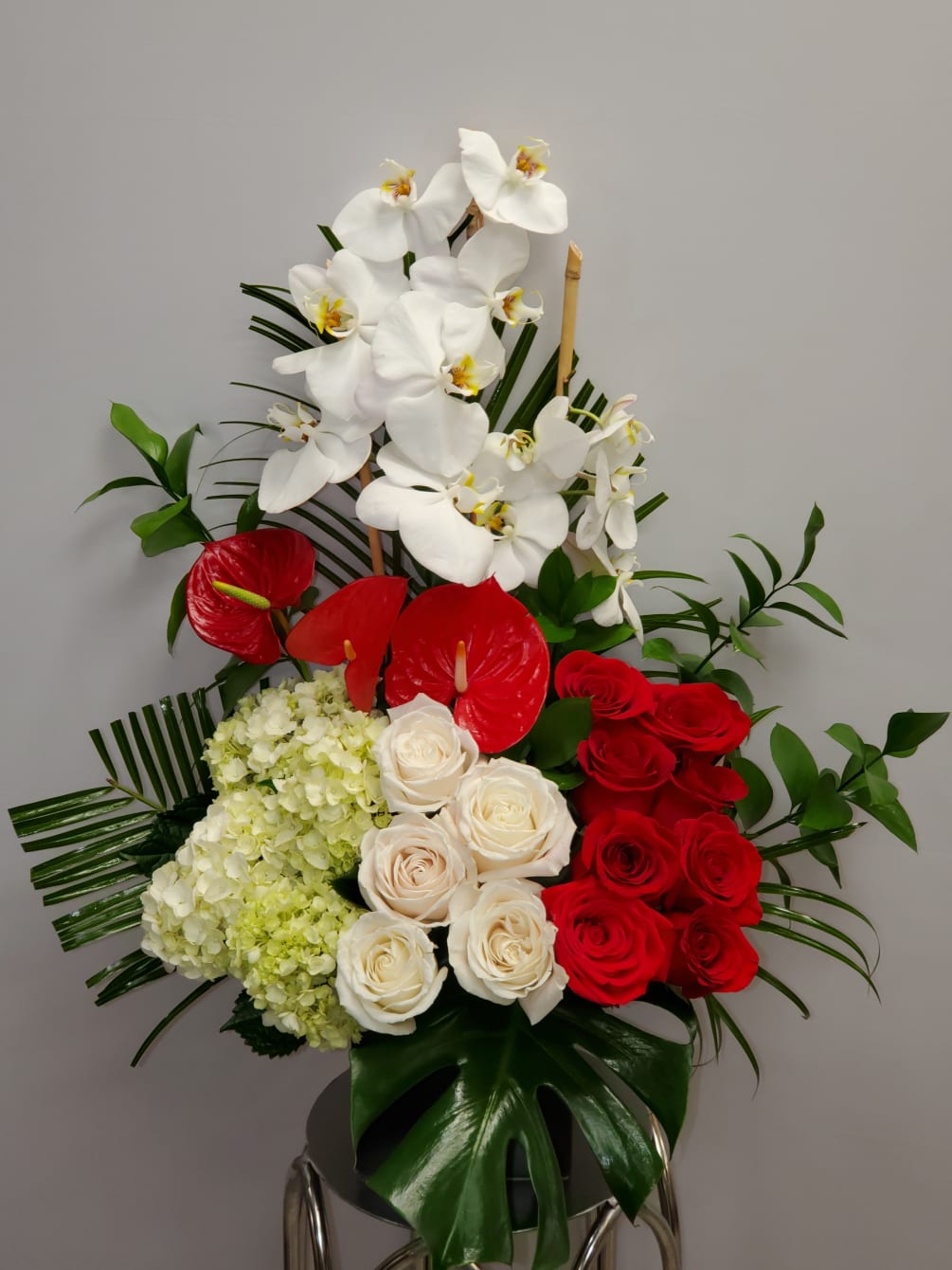 Tropical romance is a beautiful romantic arrangement with orchid, roses, hydrangea and