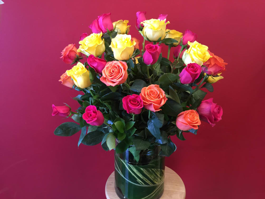 3 dozen mixed colored roses arranged perfectly in a clear glass vase