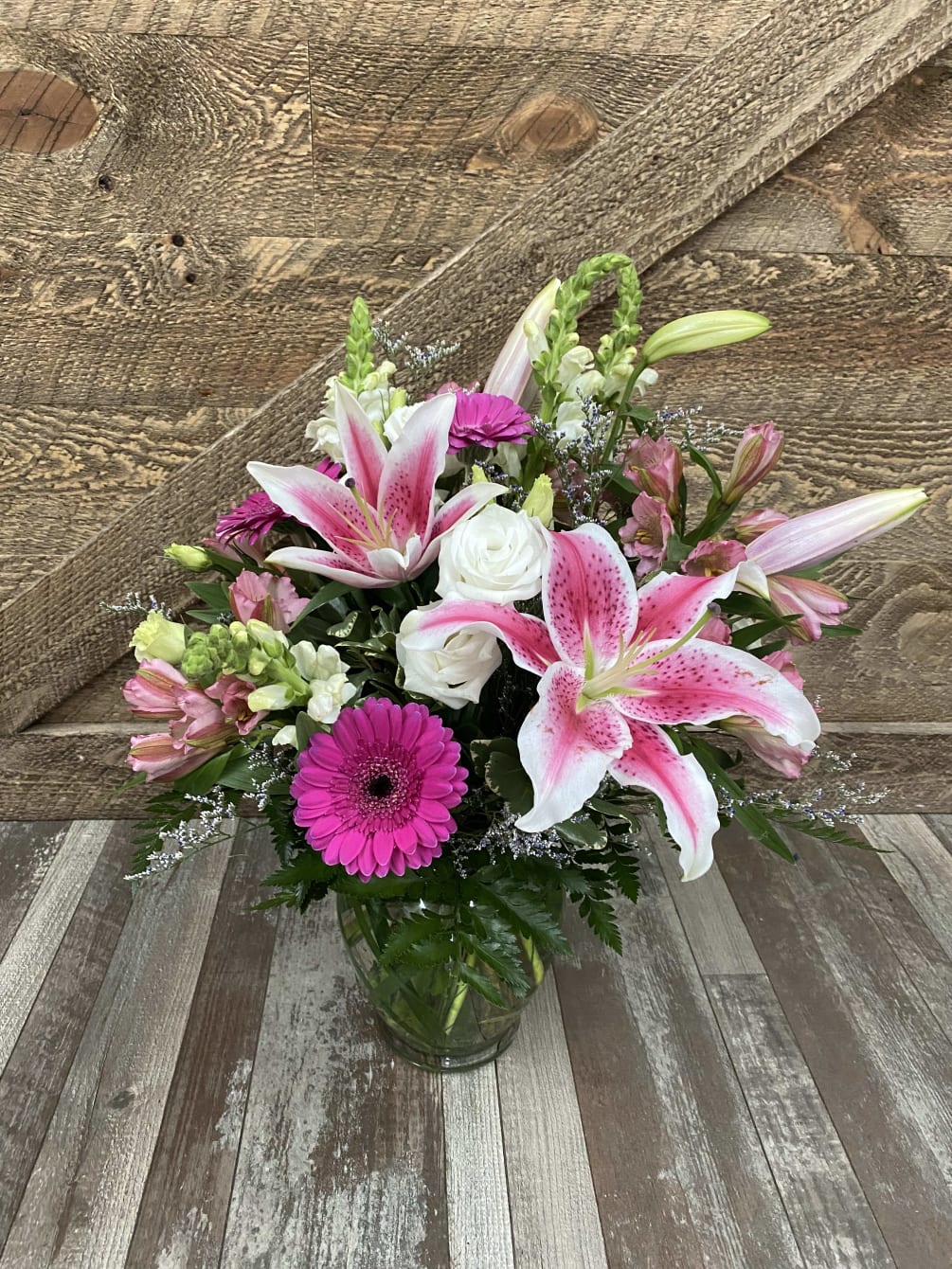 This vase arrangement includes an assortment of pink shades. Beautiful lilies, gerbera