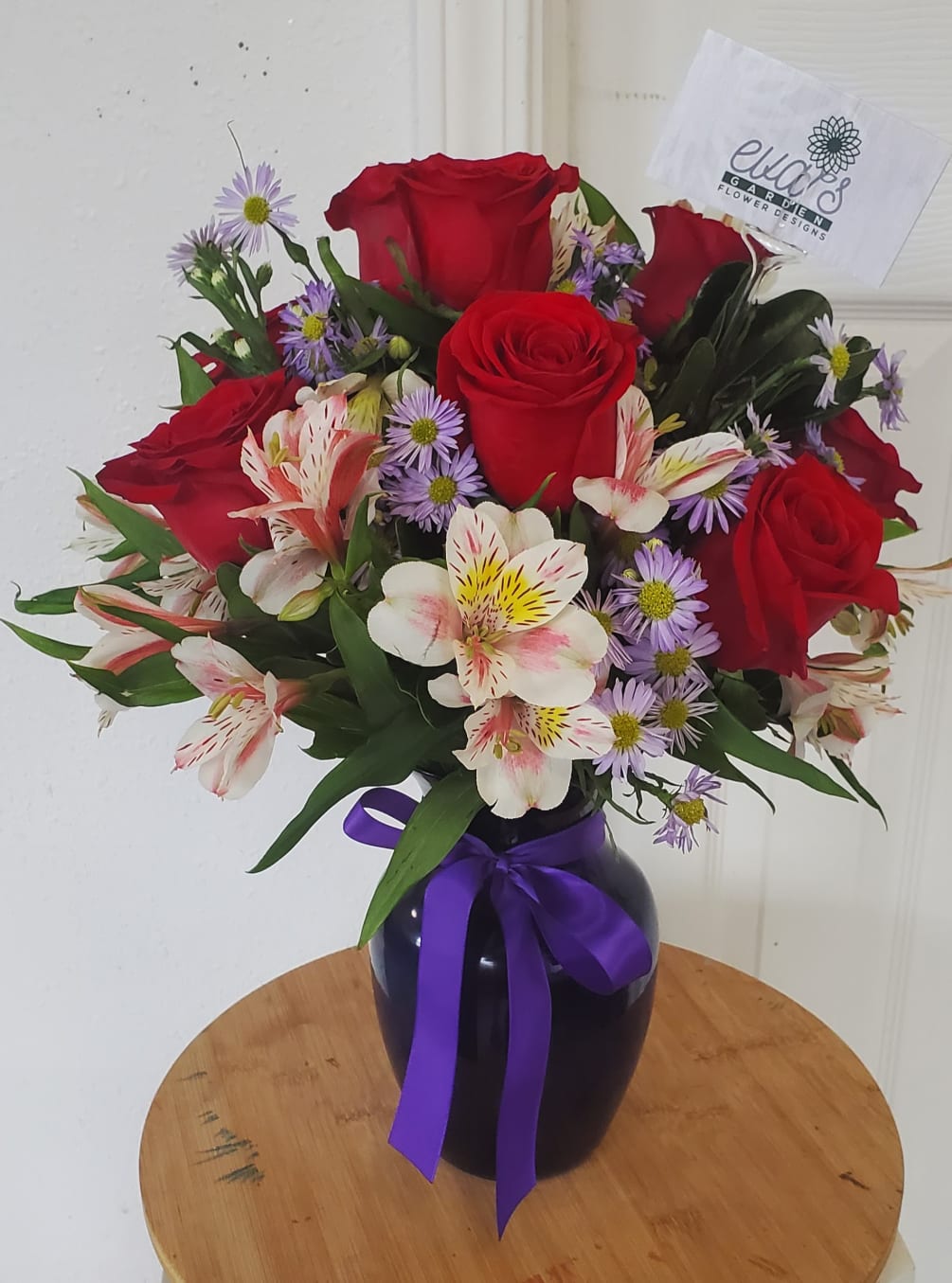 Beautiful blue crystal vase with 9 red roses, various stems of alstroemeria