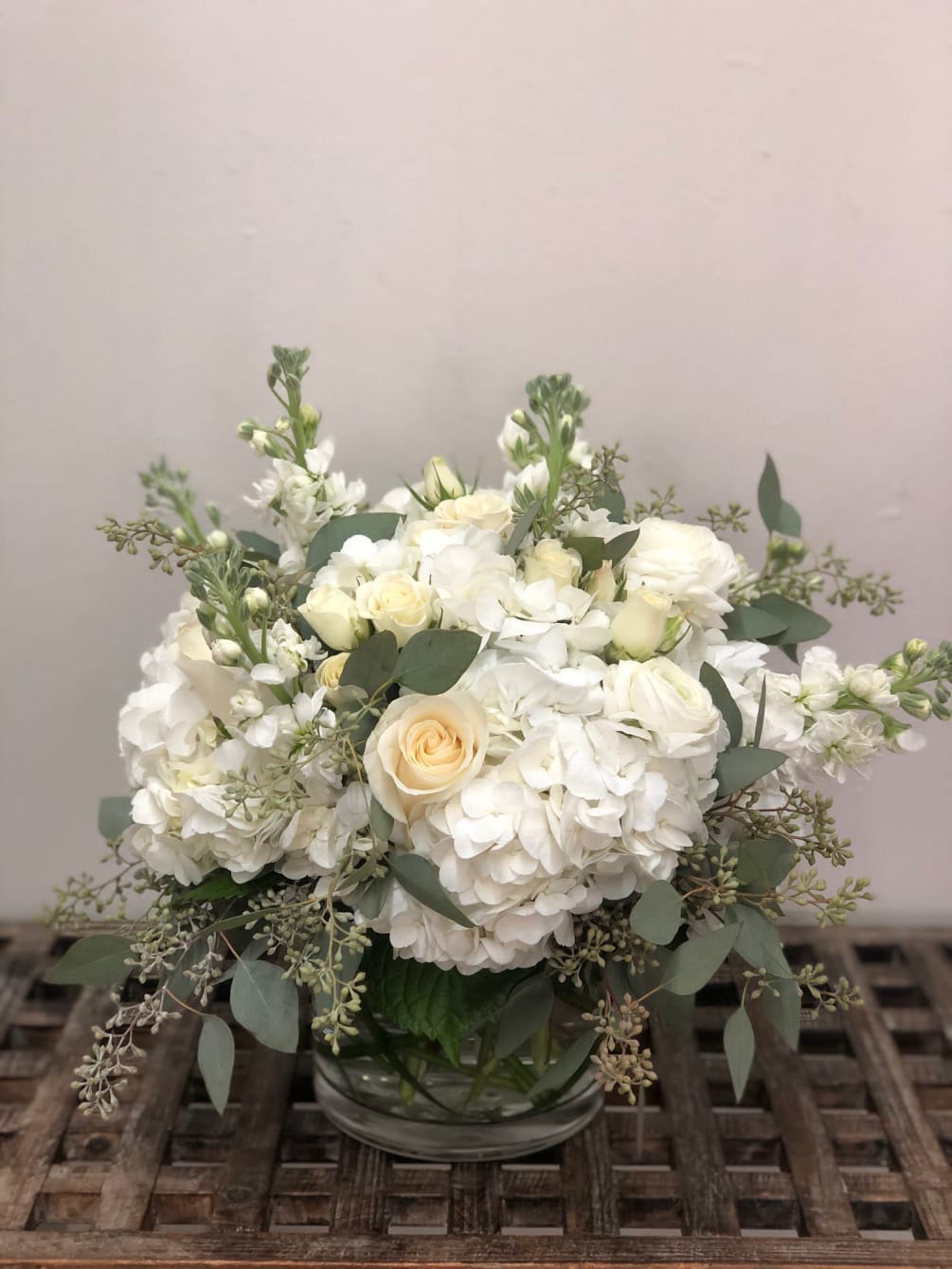 Assortment of all white flowers, pretty soft greenery in a low vase.

Flowers
