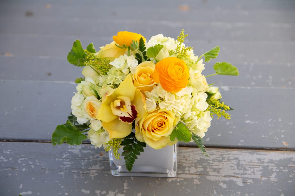 A compact, more modern style arrangement featuring roses, spray roses, hydrangea, and