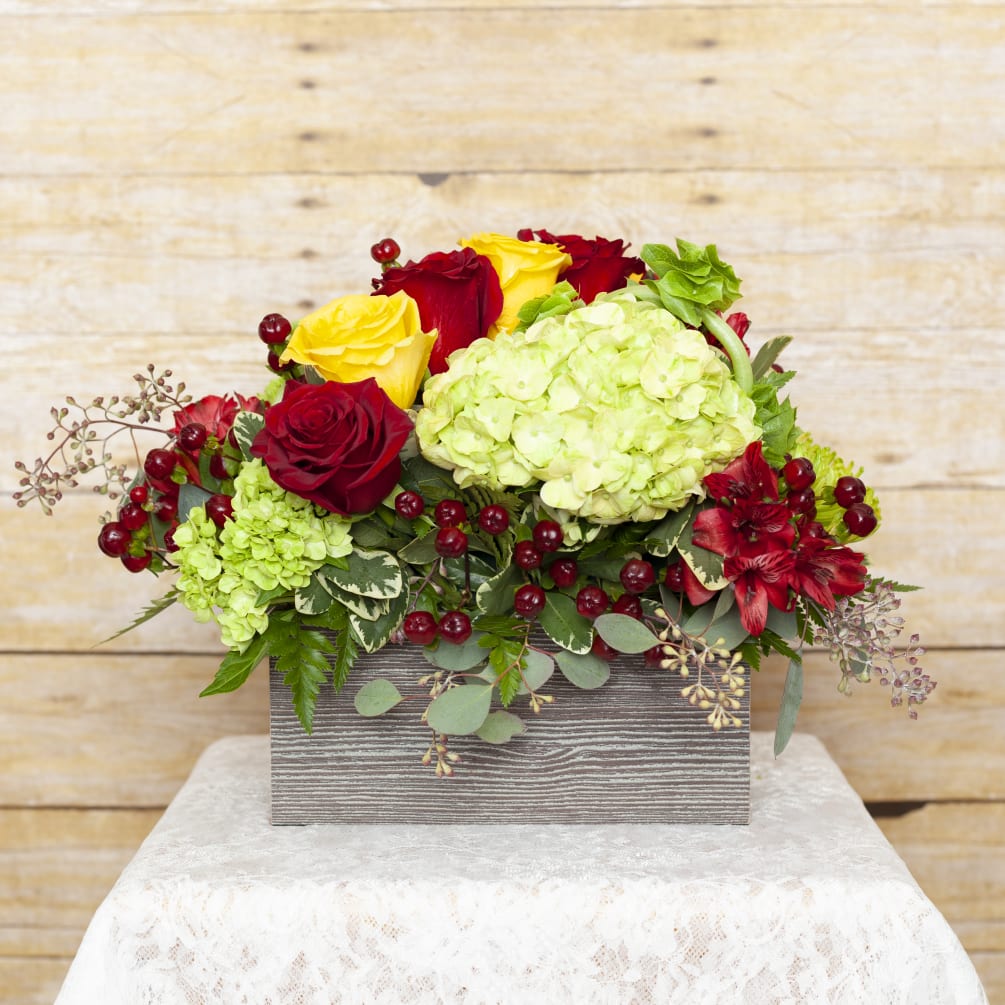 A modern wooden box filled with yellow and red roses, green hydrangea