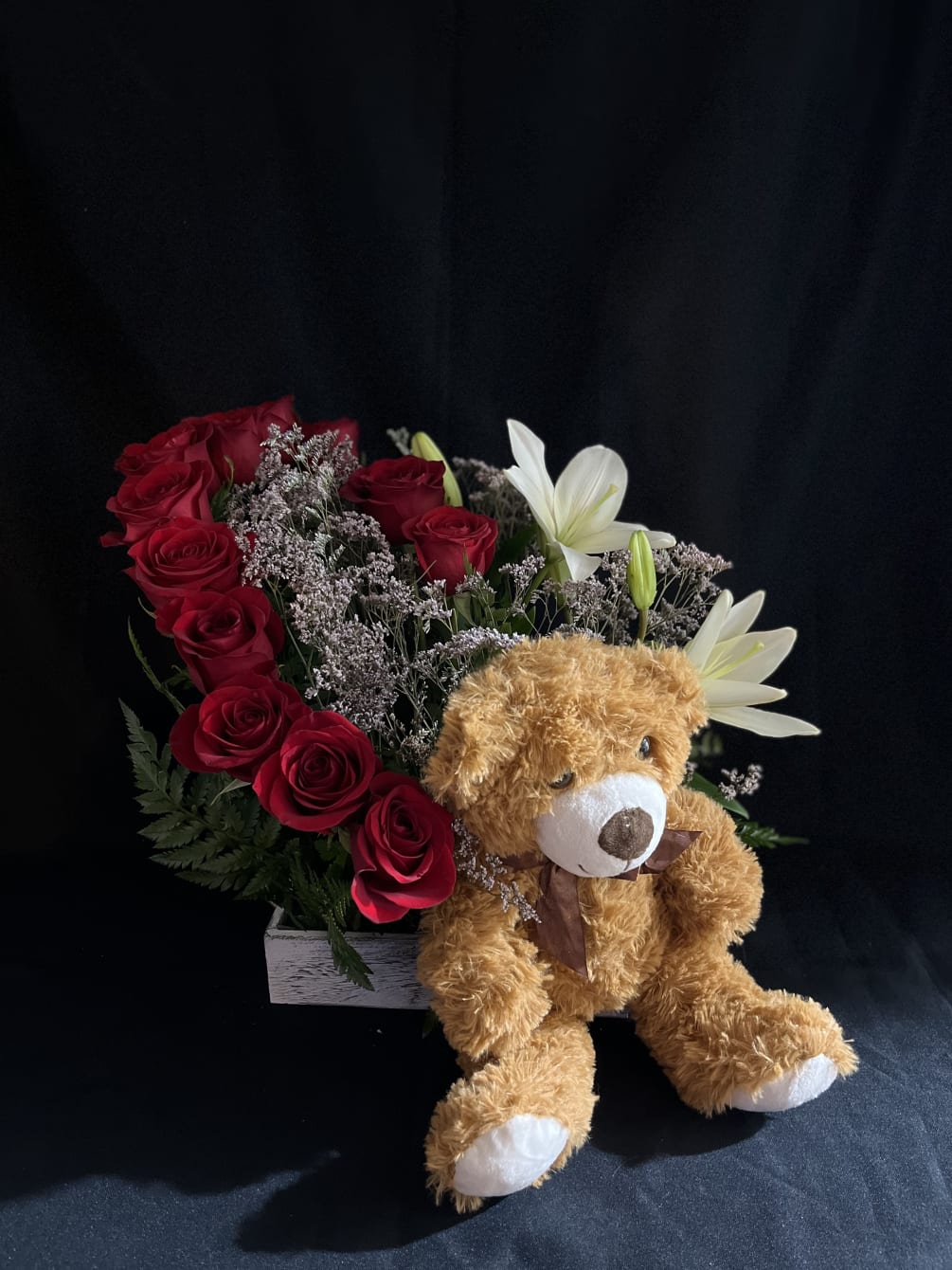 A dozen roses, lilies, with limonium, green foliage and a teddy bear.