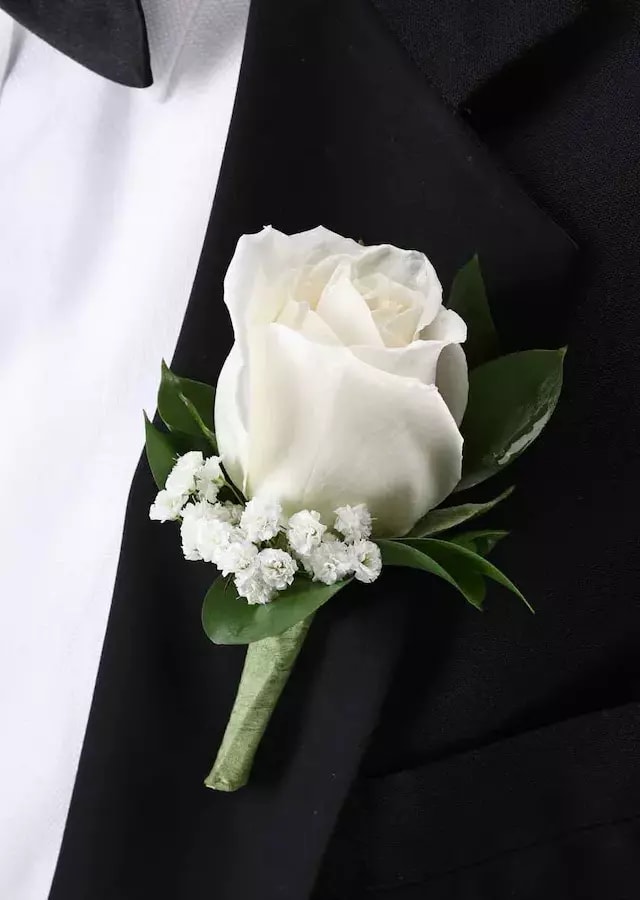 A classic white rose with a hint of greenery and accent of