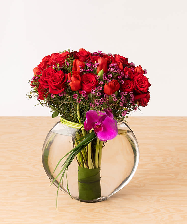 Red roses and tulips pair perfectly over a bed of magenta wax