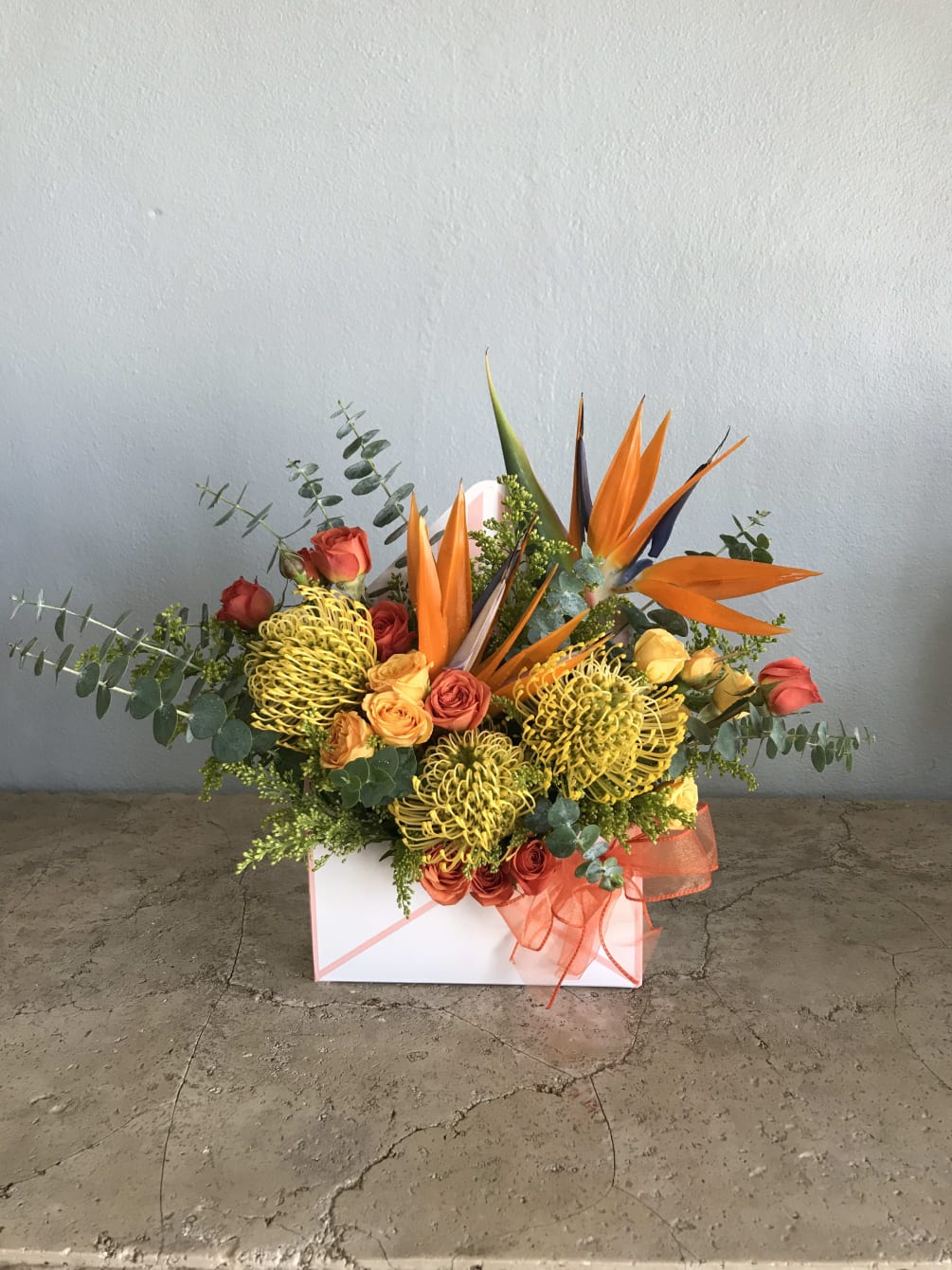 Bright orange birds of paradise dancing with golden pin cushion proteas. 