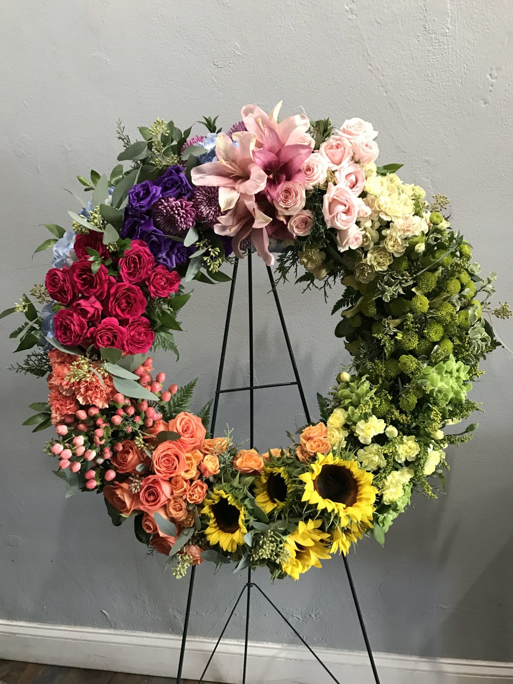 A circular wreath with warm, fun, colorful flowers. A demonstration of love